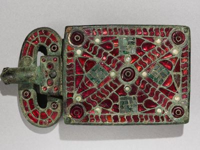 Which type of belt buckle features a decorative plate with intricate designs?