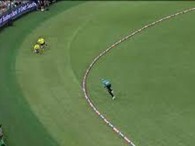 What happens if a fielder catches a ball but steps on or beyond the boundary rope at the same time?