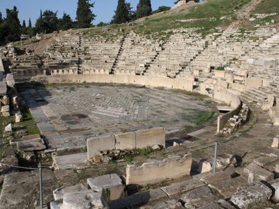 What was the name of the structure used as the backdrop for performances in ancient Greek theater?