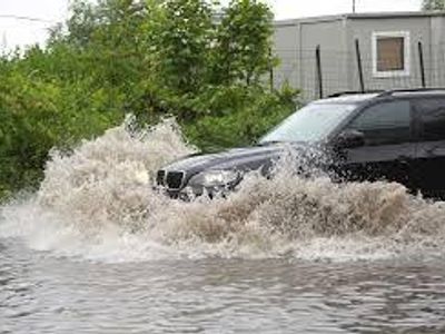 How should you handle driving through flooded roads?