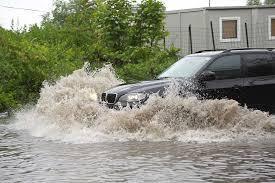 How should you handle driving through flooded roads?